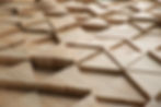 Wooden panels with a geometric pattern of raised triangles create a textured surface. The natural wood grain features warm, earthy tones.
